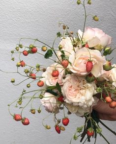 a person holding a bouquet of flowers and strawberries