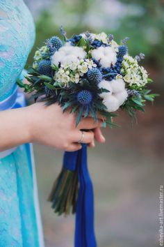 a woman holding a bouquet of flowers in her hand with blue ribbon around it's wrist