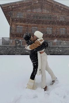 two people standing in the snow hugging each other