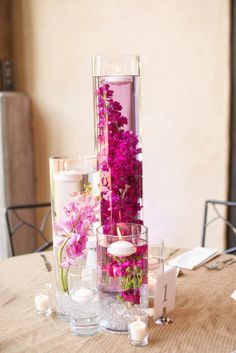 flowers and candles are arranged in glass vases on a dining room table for an elegant centerpiece