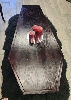 a table with two red candles on it and a black rug in the floor next to it