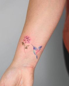 a woman's arm with a small tattoo on the wrist and a pink rose