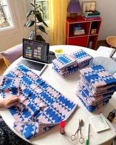 a table topped with lots of blue and pink cloths next to a laptop computer