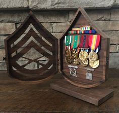 two wooden plaques with medals in them on a table next to a brick wall and stone wall