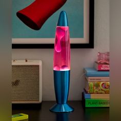 a blue and pink lamp sitting on top of a table next to a book shelf