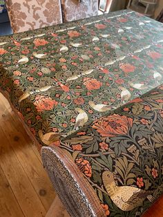 an image of a table setting with flowers and birds on the table cloth, ready to be used as a centerpiece