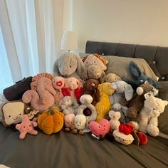 a pile of stuffed animals sitting on top of a bed