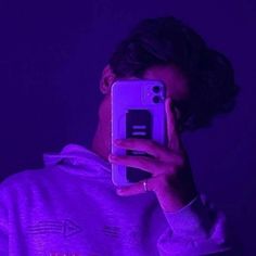 a person taking a selfie with their cell phone in the dark, while wearing a purple hoodie