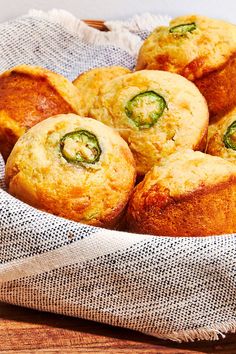 several muffins sitting in a basket on top of a wooden table next to a napkin