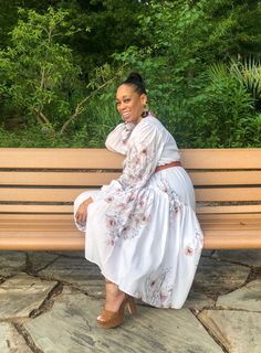 a woman in a white dress sitting on a wooden bench