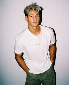 a man with blonde hair standing in front of a white wall