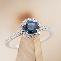 a blue diamond ring sitting on top of a wooden stand