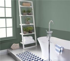 a white bath tub sitting next to a bathroom sink under a window with purple walls