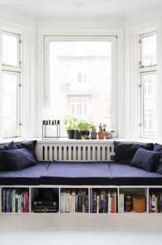 a couch sitting in front of a window next to a book shelf filled with books