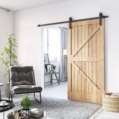 an open sliding door in a living room with a grey chair and potted plant