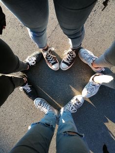 four people standing in a circle with their feet crossed on the ground, looking down at them