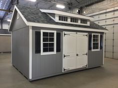 a storage shed with two doors and windows on the roof, in a large building