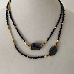 Wear this asymmetrical necklace long or double wrap it for a short necklace. Onyx gemstones are mixed with gold bars and gold beads. This necklaces is approximately 40 inches long. Black Handmade Necklace For Layering, Handmade Black Necklace For Layering, Long Gemstone Bead Necklace For Layering, Long Gemstone Beads Necklace For Layering, Gold Necklaces With Black Beads Long Shape, Layering Double Strand Natural Stone Necklaces, Gold Onyx Beaded Necklaces With Gemstone Beads, Gold Onyx Gemstone Beaded Necklaces, Layering Double Strand Beaded Necklaces With Natural Stones