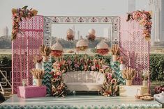 an outdoor wedding setup with pink, green and gold decorations on the stage area for guests to sit down