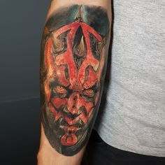 a man with a tattoo on his arm has a red and black mask on it