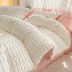 a bed with white and pink comforters on it