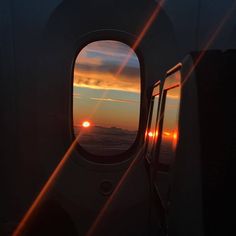 the sun is setting over the ocean as seen through an airplane's porthole window