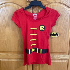 a red shirt with batman on it hanging from a wooden door