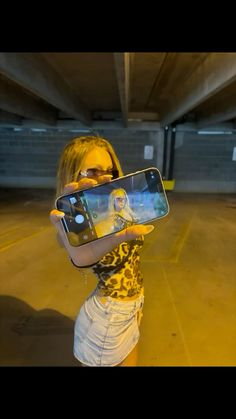 a woman taking a selfie with her cell phone in an empty parking garage area