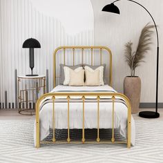 a gold bed with two pillows on it and a lamp in the corner next to it