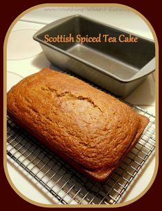 a loaf of scottish spiced tea cake sitting on a cooling rack next to a pan