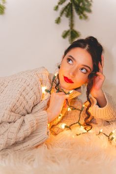 a woman laying on the floor with christmas lights around her neck and hands behind her head