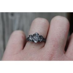 a person's hand holding an engagement ring with three stones on top of it