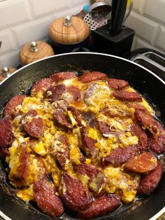 a skillet filled with eggs and sausages on top of a stove burner