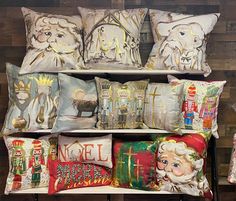 decorative pillows are displayed on a shelf in front of a wooden wall with santa claus and other christmas decorations