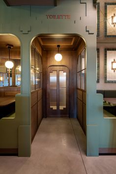 the entrance to a building with wooden doors and windows on both sides is lit by round lights