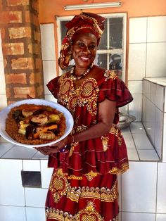 a woman in a red and gold dress holding a white plate with food on it