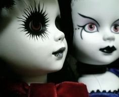 two creepy dolls with red eyes and black hair