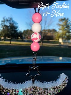 a pink and white necklace hanging from the back of a car