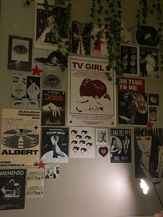 there are many posters on the wall and one is lit up with a lamp next to it