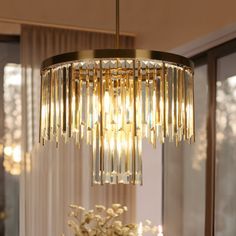 a chandelier hanging over a dining room table with flowers and candles on it