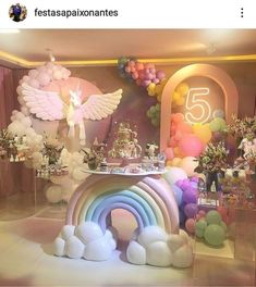 a room with balloons and decorations on the walls, including a rainbow table set up for a birthday party