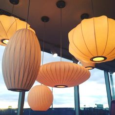 several lamps hanging from the ceiling in a room with large windows and lots of lights