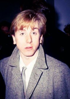 a man with blonde hair wearing a suit and tie in front of a group of people