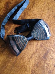 a wooden table topped with a black bow tie and a blue bag on top of it