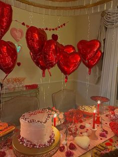 a table topped with lots of heart shaped balloons next to a cake and cupcakes