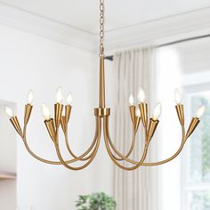 a gold chandelier hanging from a ceiling in a room with white walls and curtains