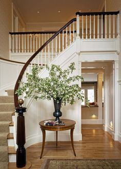 a vase with flowers sitting on top of a table in front of a stair case