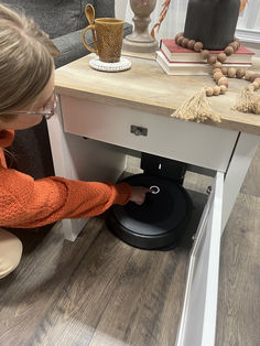 This innovative side table provides space-saving concepts by stylishly blending hidden space for your robot vacuum with the function of a storage side table. The easy-open door of this robot vacuum storage conceals and quiets the operation of self-emptying docking stations, while the open bottom design allows the vacuum disc easy access and compatibility with most disc style robots and top loading docking stations. Robot Vacuum Cleaner Storage, Laundry Room Vacuum Storage, Robot Vacuum Storage Ideas, Hidden Robot Vacuum Storage, Irobot Roomba Storage Ideas, Roomba Storage Idea, Hide Robot Vacuum, Robot Vacuum Storage, Vacuum Cleaner Storage