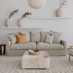 square hair on hide ottoman with a small woven tray on top on a rug and in front of a loose cover sofa Statement Coffee Table, Hide Ottoman, Two Ottomans, Leather Braiding, Cowhide Ottoman, Geometric Floor, Create A Signature, Velvet Ottoman, Bench Set