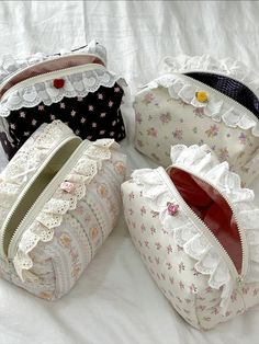 four purses are lined up on a white sheet, one has lace and the other has flowers